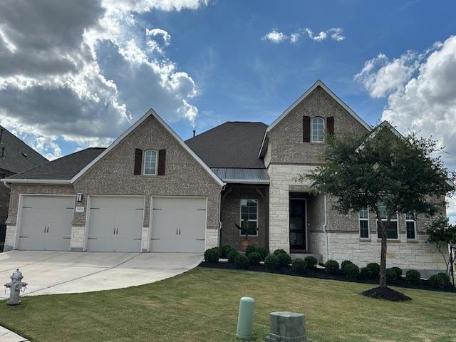 900 Elenora Dr, Leander, TX 78641 - view of front of property featuring an attached garage, concrete driveway, a front lawn, stone siding, and brick siding