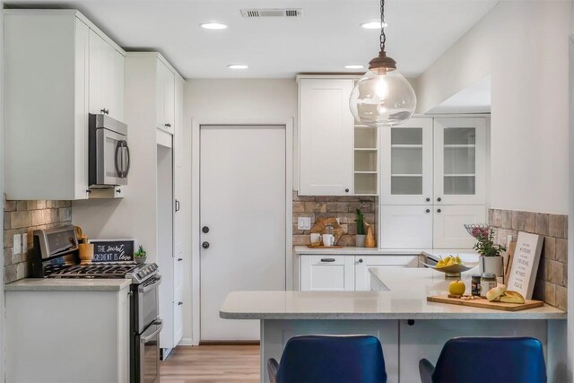 4504 Bilboa Dr, Austin, TX 78759 - kitchen featuring appliances with stainless steel finishes, backsplash, a peninsula, white cabinets, and recessed lighting