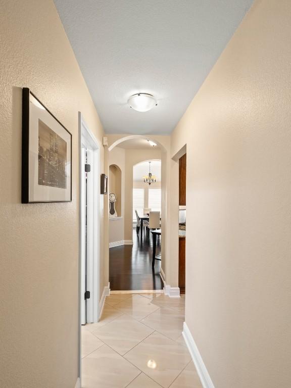 2520 Butler National Dr, Pflugerville, TX 78660 - hallway with arched walkways, a chandelier, and light tile patterned flooring