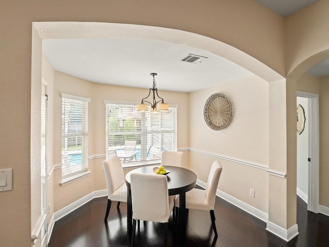2520 Butler National Dr, Pflugerville, TX 78660 - dining space with dark wood-style floors, arched walkways, and a chandelier
