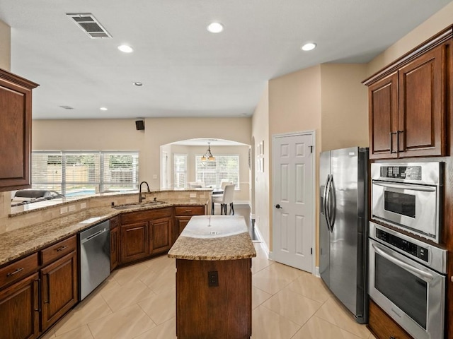 2520 Butler National Dr, Pflugerville, TX 78660 - kitchen with appliances with stainless steel finishes, arched walkways, plenty of natural light, light stone countertops, and recessed lighting