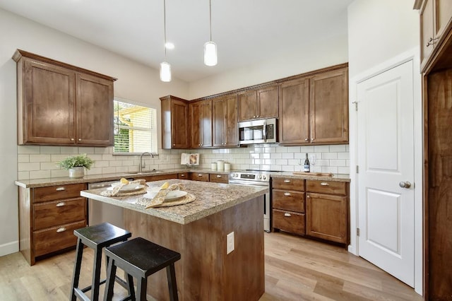 2109 Meadow View Dr, San Marcos, TX 78666 - kitchen with appliances with stainless steel finishes, light wood-type flooring, a kitchen bar, and decorative backsplash