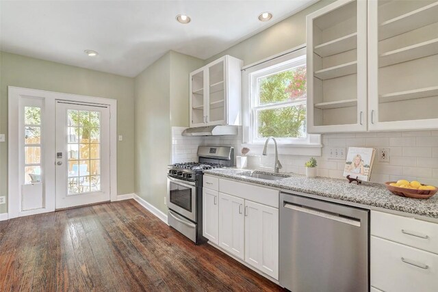 4412 Red River St, Austin, TX 78751 - kitchen with stainless steel appliances, dark wood-style floors, light stone counters, glass insert cabinets, and tasteful backsplash