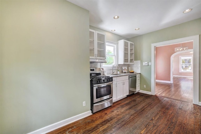 4412 Red River St, Austin, TX 78751 - kitchen with appliances with stainless steel finishes, glass insert cabinets, white cabinets, dark wood-style floors, and decorative backsplash