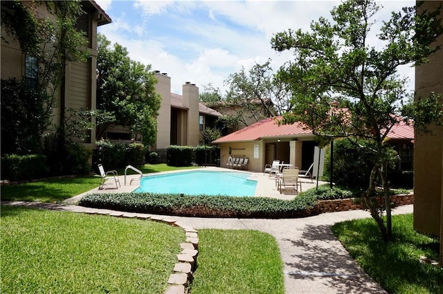 community pool with a patio and a lawn