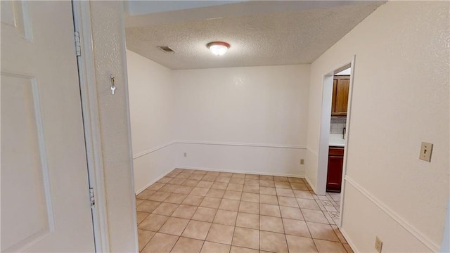 unfurnished room featuring a textured ceiling and light tile patterned floors
