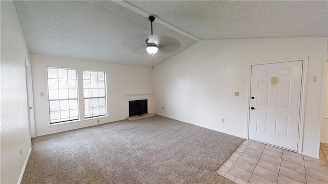 unfurnished living room with a ceiling fan, lofted ceiling, a textured ceiling, light colored carpet, and a fireplace with raised hearth