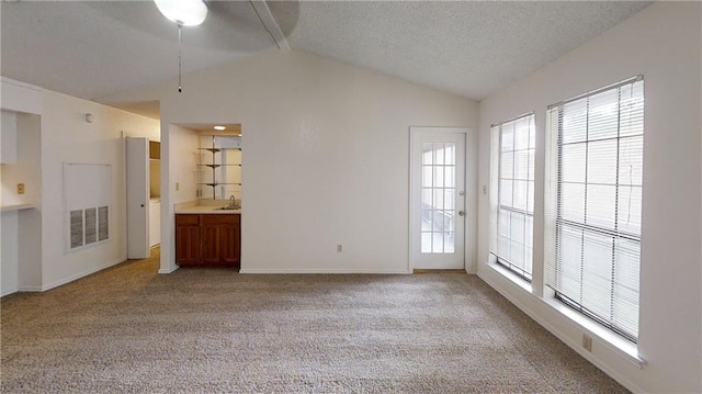 unfurnished living room featuring lofted ceiling, light carpet, and a textured ceiling