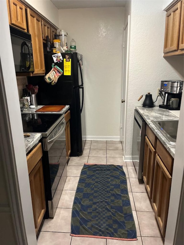 kitchen featuring stainless steel appliances, light tile patterned floors, and brown cabinets