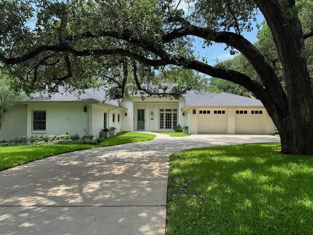1904 Meadowbrook Dr, Austin, TX 78703 - ranch-style home with concrete driveway, a front yard, an attached garage, french doors, and brick siding