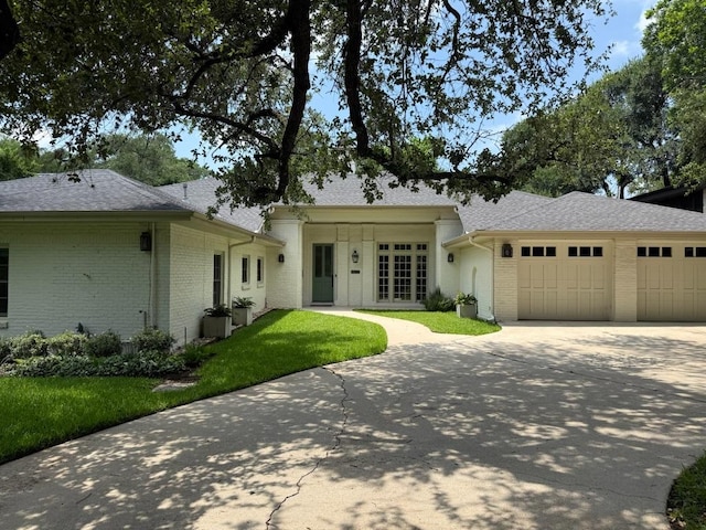 1904 Meadowbrook Dr, Austin, TX 78703 - ranch-style home with driveway, brick siding, a garage, a front lawn, and roof with shingles