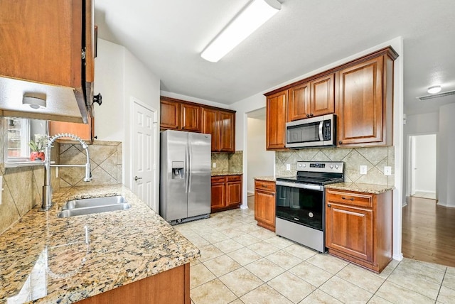 1921 Sand Creek Rd, Cedar Park, TX 78613 - kitchen featuring appliances with stainless steel finishes, tasteful backsplash, and light stone countertops