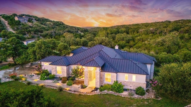 2250 Meritage, New Braunfels, TX 78132 - view of front facade featuring a standing seam roof, stone siding, a wooded view, a metal roof, and stucco siding
