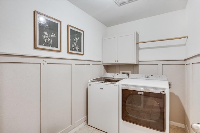 605 Liard River Rd, Hutto, TX 78634 - washroom featuring washing machine and clothes dryer, a decorative wall, cabinet space, wainscoting, and light tile patterned floors
