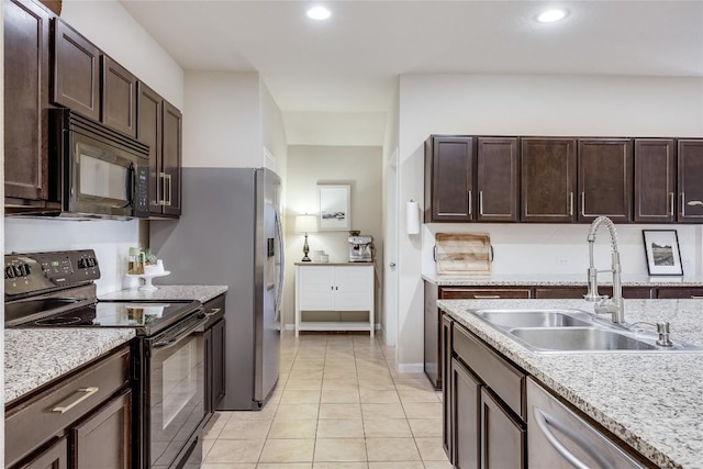 605 Liard River Rd, Hutto, TX 78634 - kitchen with black appliances, dark brown cabinets, light tile patterned floors, recessed lighting, and light stone countertops