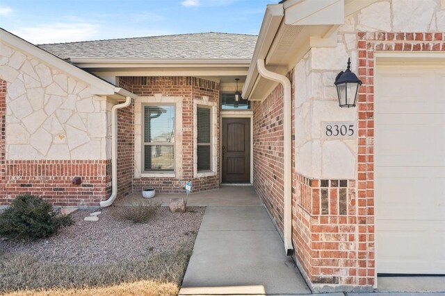 8305 Split Trail Cv, Temple, TX 76502 - property entrance featuring a garage, stone siding, a shingled roof, and brick siding