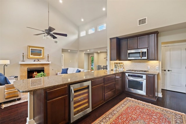 4104 Honeycomb Rock Cir, Austin, TX 78731 - kitchen with wine cooler, stainless steel appliances, open floor plan, light stone countertops, and dark wood-style flooring