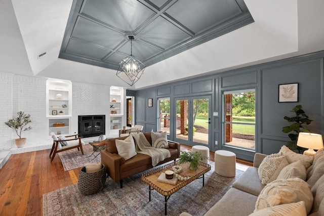 3501 Lost Pine Cv, Austin, TX 78739 - living area featuring a decorative wall, wood-type flooring, built in shelves, a brick fireplace, and a chandelier