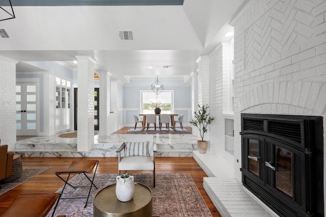 3501 Lost Pine Cv, Austin, TX 78739 - living room featuring crown molding, wood finished floors, decorative columns, a fireplace, and a wainscoted wall