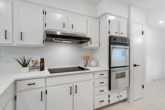 8432 Antero Dr, Austin, TX 78759 - kitchen with stainless steel double oven, under cabinet range hood, black electric cooktop, light tile patterned floors, and white cabinets