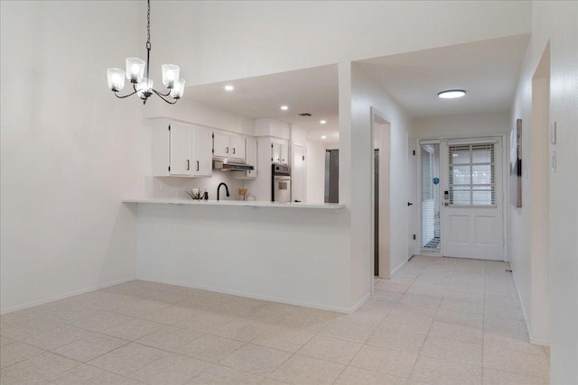 8432 Antero Dr, Austin, TX 78759 - kitchen with oven, light countertops, under cabinet range hood, a chandelier, and white cabinetry