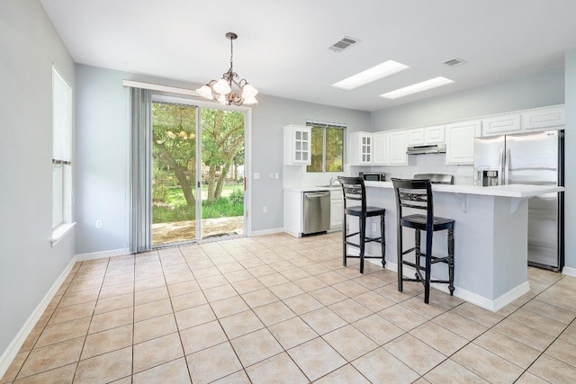 113 Stetson Trl, Georgetown, TX 78633 - kitchen with appliances with stainless steel finishes, under cabinet range hood, light countertops, a kitchen bar, and a chandelier