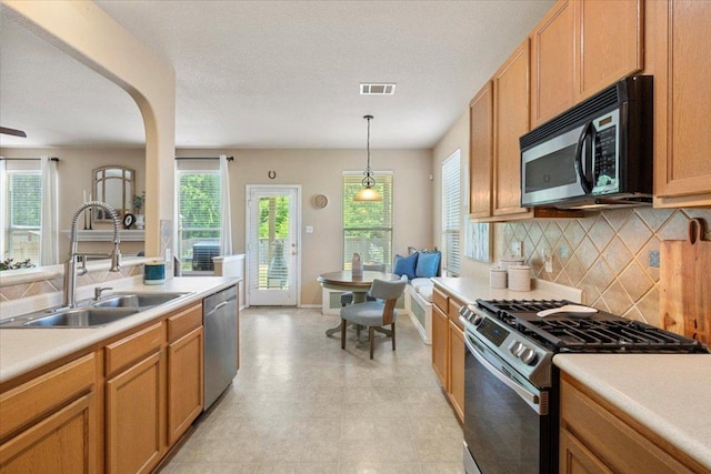 2818 Shadowpoint Cv, Round Rock, TX 78665 - kitchen featuring stainless steel appliances, light countertops, decorative backsplash, decorative light fixtures, and arched walkways