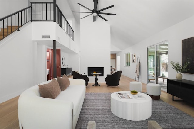 11707 Barrington Way, Austin, TX 78759 - living room featuring a ceiling fan, wood finished floors, a warm lit fireplace, high vaulted ceiling, and stairway
