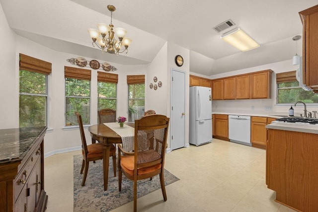 1831 Greening Way, Leander, TX 78641 - kitchen featuring white appliances, a chandelier, hanging light fixtures, vaulted ceiling, and brown cabinets