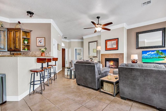 2207 Stonehaven, San Marcos, TX 78666 - living area with a ceiling fan, light tile patterned floors, a tile fireplace, and crown molding