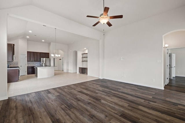 6042 Roma St, Round Rock, TX 78665 - unfurnished living room featuring arched walkways, lofted ceiling, ceiling fan, wood finished floors, and a chandelier