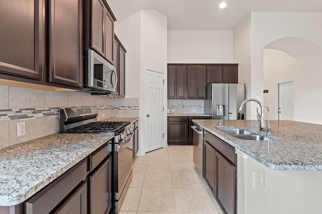 6042 Roma St, Round Rock, TX 78665 - kitchen with appliances with stainless steel finishes, arched walkways, dark brown cabinetry, backsplash, and light stone countertops