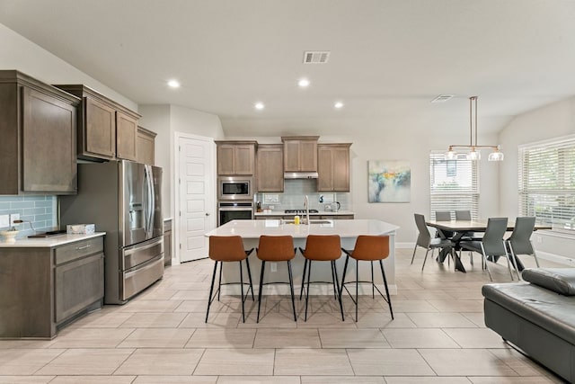 904 Astoria St, Cedar Park, TX 78613 - kitchen with stainless steel appliances, decorative backsplash, light countertops, a breakfast bar area, and under cabinet range hood