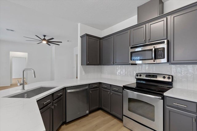 204 S Meadowlark St, Lakeway, TX 78734 - kitchen featuring stainless steel appliances, light wood-type flooring, light stone counters, backsplash, and a ceiling fan