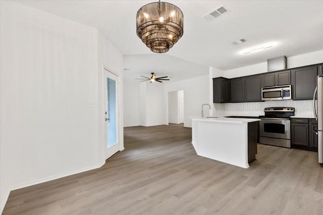 204 S Meadowlark St, Lakeway, TX 78734 - kitchen featuring appliances with stainless steel finishes, light wood-style flooring, tasteful backsplash, open floor plan, and a chandelier