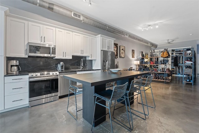 2124 E 6th St Unit 319, Austin, TX 78702 - kitchen with appliances with stainless steel finishes, finished concrete floors, dark countertops, and backsplash