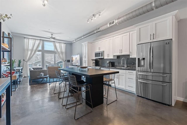 2124 E 6th St Unit 319, Austin, TX 78702 - kitchen with appliances with stainless steel finishes, dark countertops, finished concrete floors, and decorative backsplash