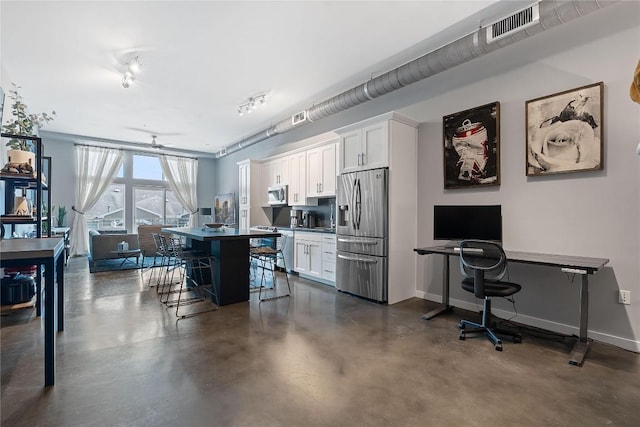 2124 E 6th St Unit 319, Austin, TX 78702 - kitchen with appliances with stainless steel finishes, an office area, a kitchen bar, finished concrete flooring, and white cabinets