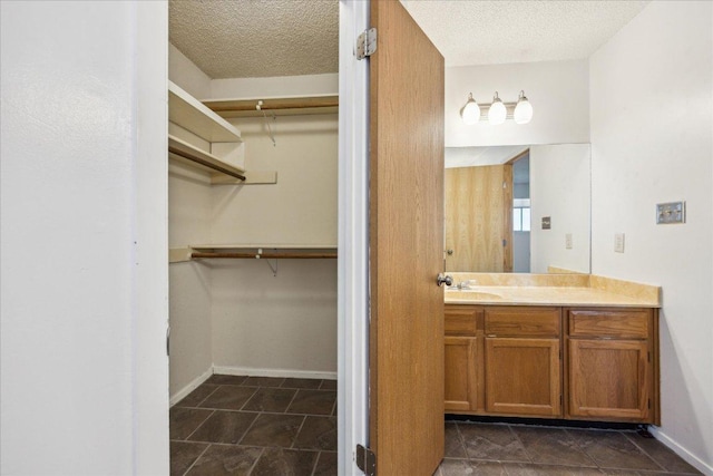 4910 Wing Rd, Austin, TX 78749 - bathroom with vanity, a spacious closet, and a textured ceiling