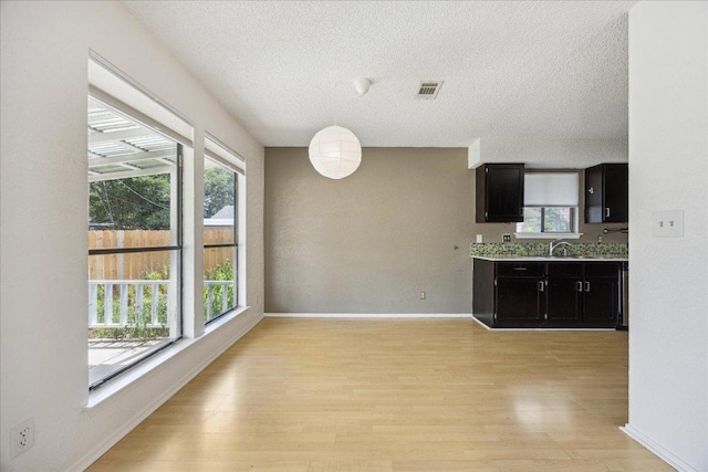4910 Wing Rd, Austin, TX 78749 - unfurnished dining area with a textured ceiling and light wood finished floors
