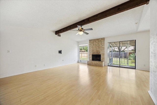 4910 Wing Rd, Austin, TX 78749 - unfurnished living room with a ceiling fan, light wood finished floors, a stone fireplace, and a textured ceiling