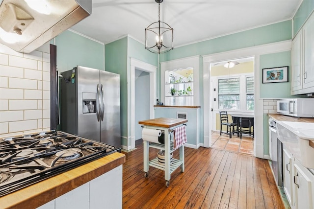 1004 Mitchell St, Gonzales, TX 78629 - kitchen with stainless steel fridge, white microwave, butcher block counters, gas cooktop, and ornamental molding