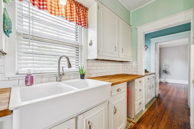 1004 Mitchell St, Gonzales, TX 78629 - kitchen with butcher block counters, decorative backsplash, dark wood-style floors, ornamental molding, and white cabinets