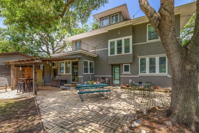 1004 Mitchell St, Gonzales, TX 78629 - rear view of house with a balcony, stucco siding, and a patio area