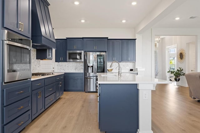 2233 Bellisa Vista Dr, Leander, TX 78641 - kitchen with appliances with stainless steel finishes, light wood finished floors, custom range hood, light countertops, and recessed lighting