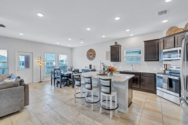 717 Friars Tuck Dr, Temple, TX 76502 - kitchen featuring appliances with stainless steel finishes, dark brown cabinets, open floor plan, a kitchen breakfast bar, and a center island