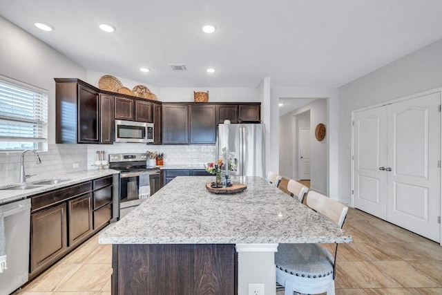 717 Friars Tuck Dr, Temple, TX 76502 - kitchen with appliances with stainless steel finishes, a kitchen island, a breakfast bar, backsplash, and recessed lighting
