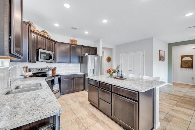 717 Friars Tuck Dr, Temple, TX 76502 - kitchen with appliances with stainless steel finishes, tasteful backsplash, a kitchen island, dark brown cabinets, and recessed lighting