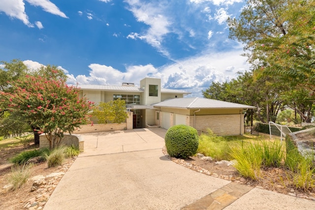 1417 Osprey Ridge Loop, Lago Vista, TX 78645 - view of front of home with a garage, concrete driveway, a metal roof, and brick siding
