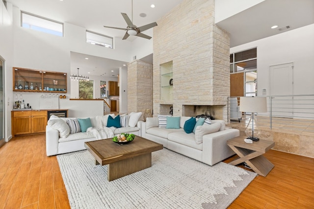 1417 Osprey Ridge Loop, Lago Vista, TX 78645 - living room featuring a ceiling fan, a high ceiling, wet bar, light wood-type flooring, and a stone fireplace